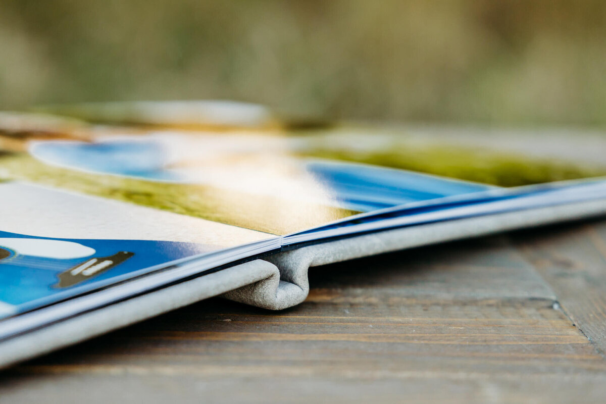 close up of the binding on an album as it lays open on a wooden table in the middle of a field