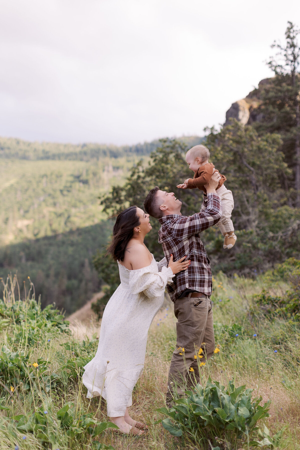 mother and father lift baby up in the air in the columbia river gorge