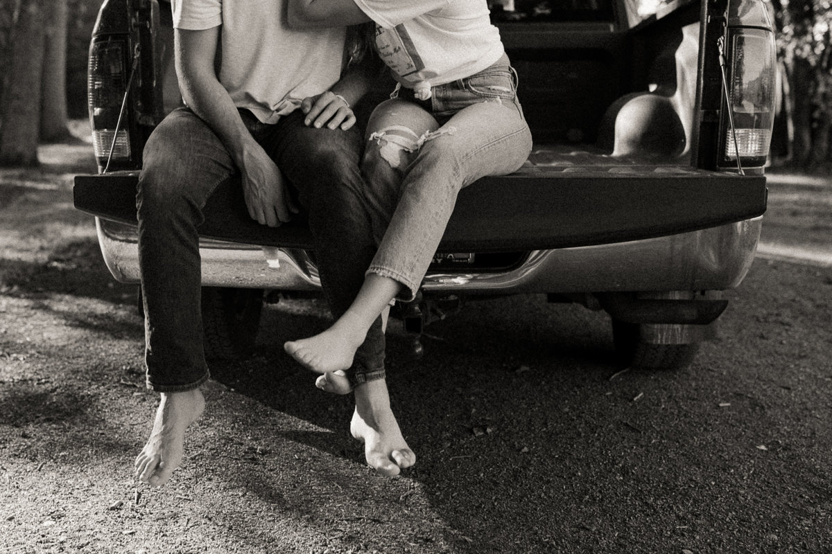 couple sitting on truck bed with their feet intertwined