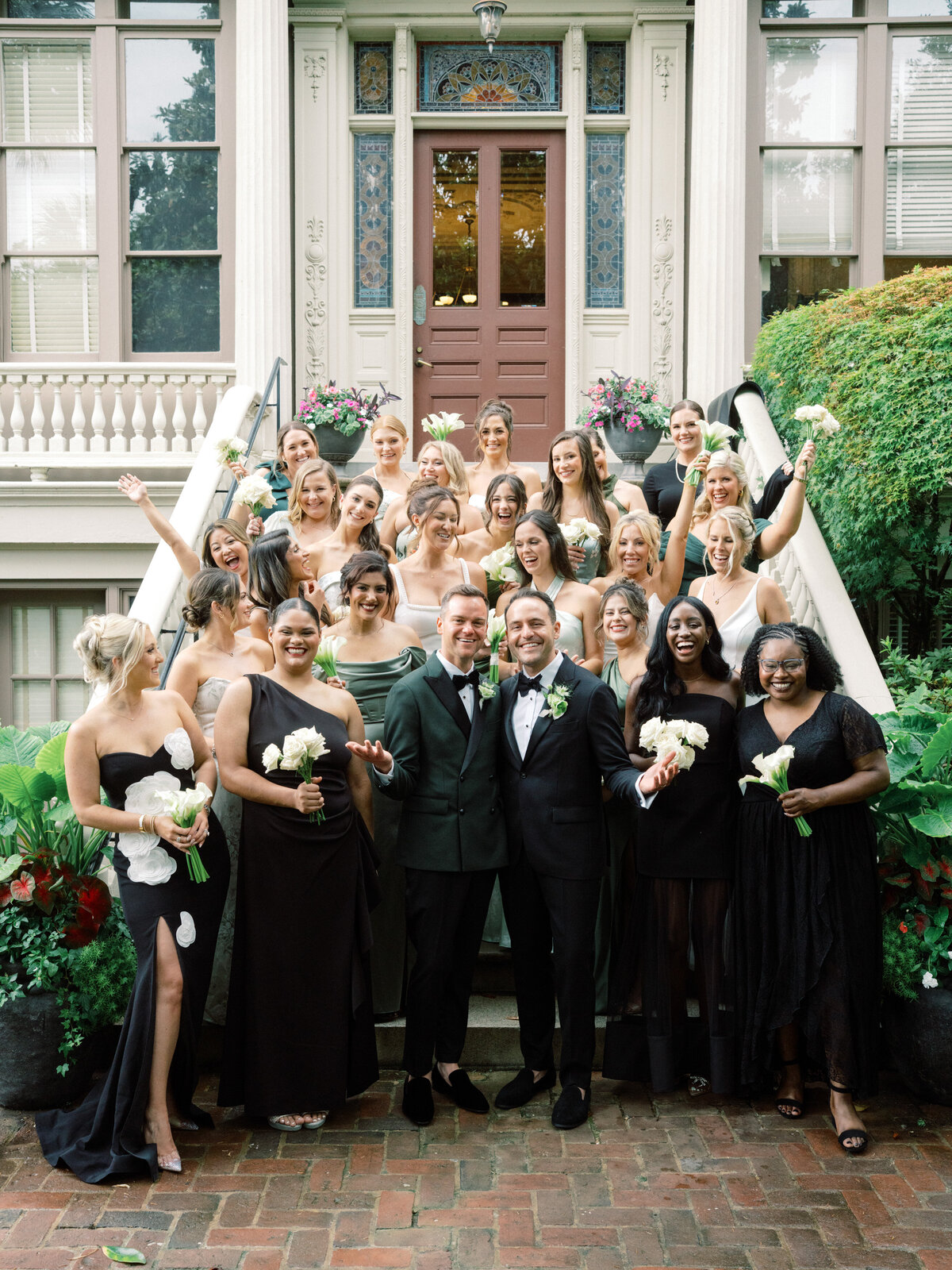 A striking photo of a wedding couple flanked by their bridesmaids, radiating happiness and style with coordinating elegant dresses and suits in a beautiful outdoor setting.