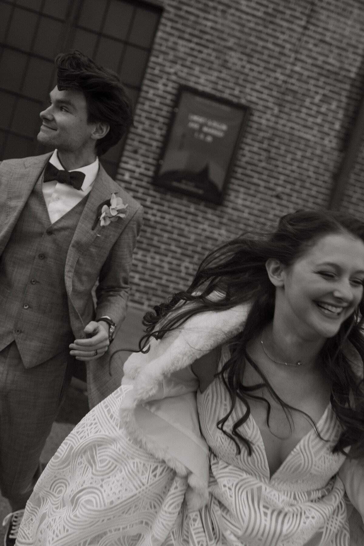 bride and groom run towards camera in black and white