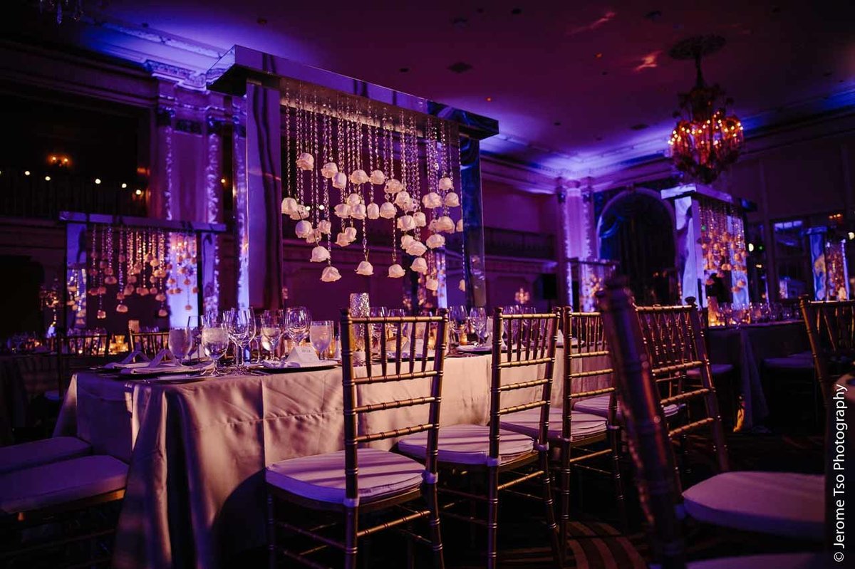 centerpiece of trailing roses on crystal strands suspended from mirrored table structure and gold Chivari chairs