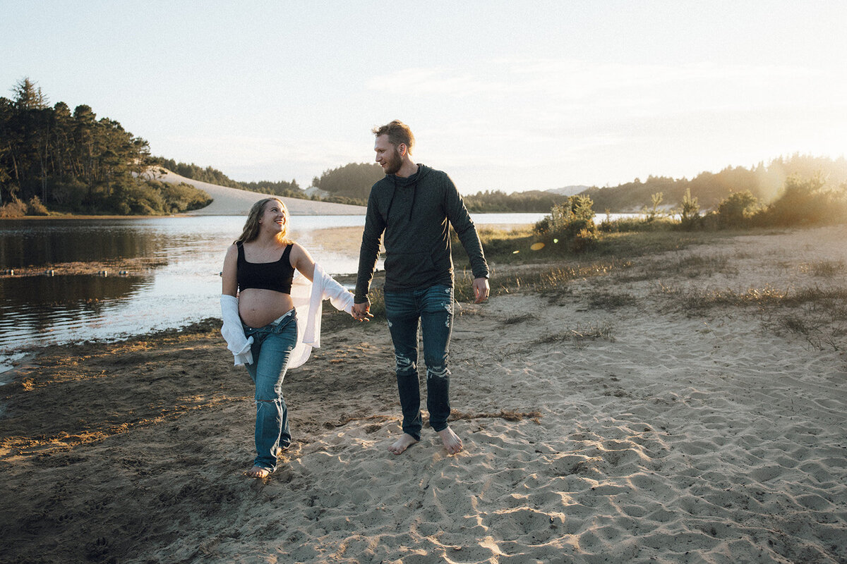 Man and woman stroll hand in hand though the sand on the beach during golden hour.