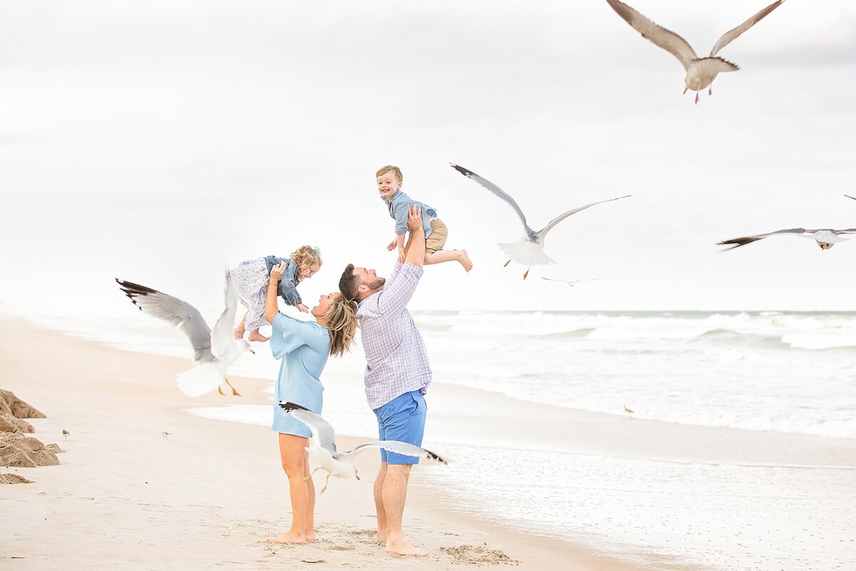 Family playing with seagulls on the beach