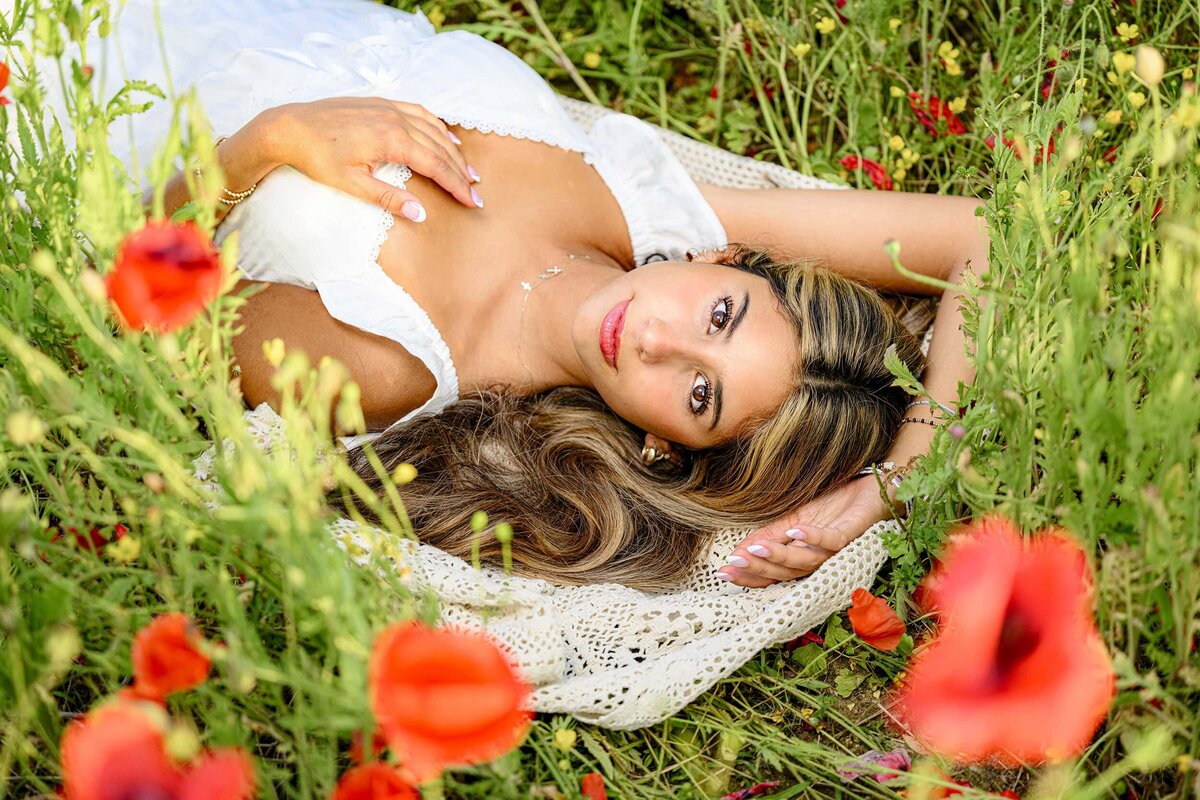 Cuthbertson High School Graduate lauys in blue hill garden flower field wearing a white dress for senior portrait session