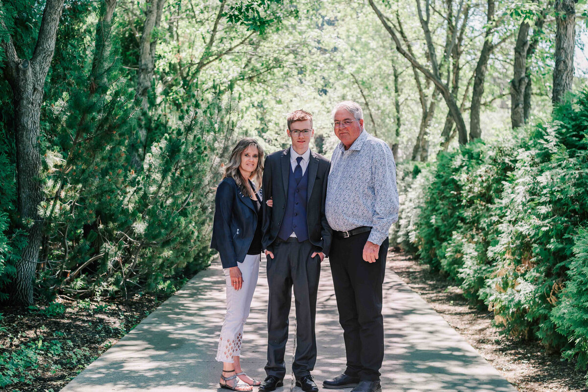 A full body portrait with the graduate and his parents. 
