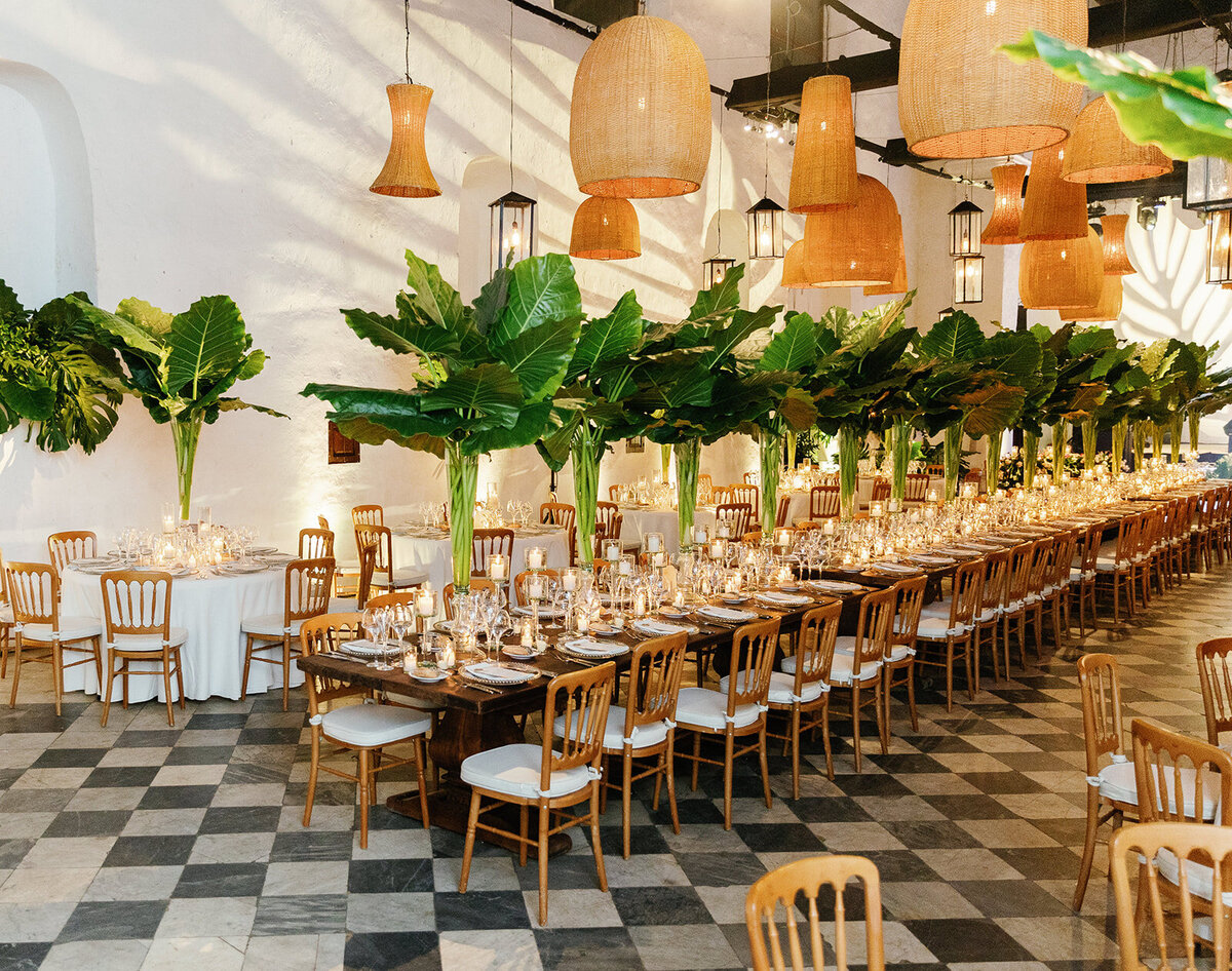 A stunning wedding reception setup featuring lush greenery, wooden accents, and warm hanging lanterns in Cartagena Colombia.