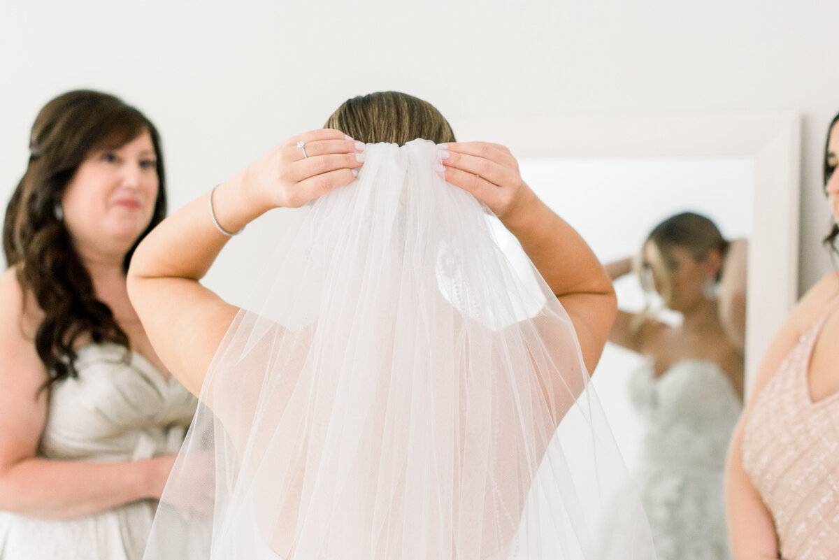Bride putting on veil with mom.