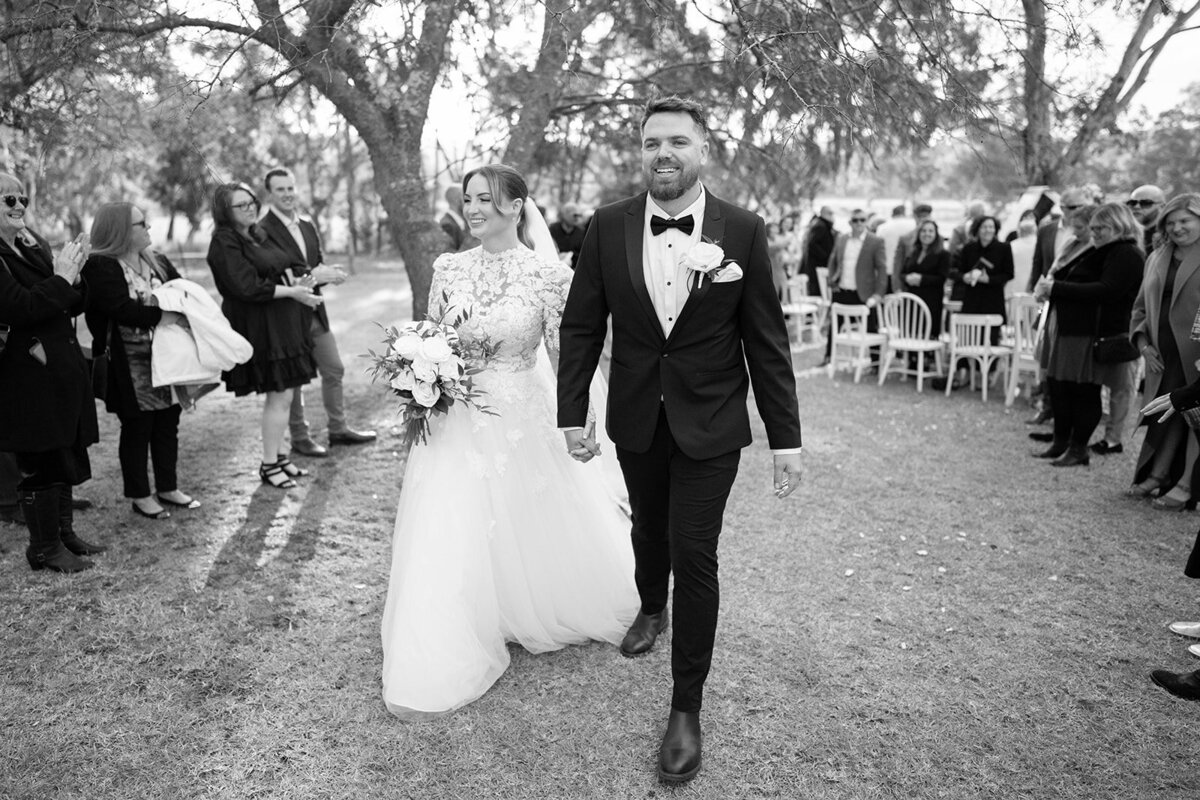 black and white photo of the couple walking back the aisle