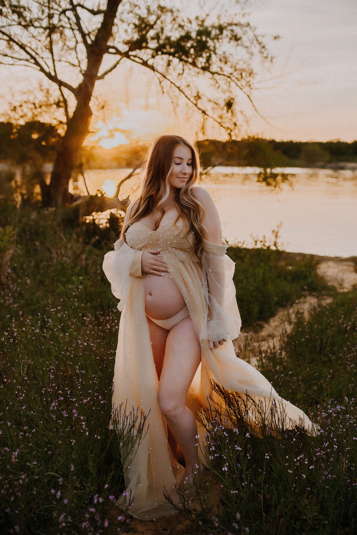 A pregnant woman in a tulle gown standing by the lake of grapevine in Flower Mound, Texas