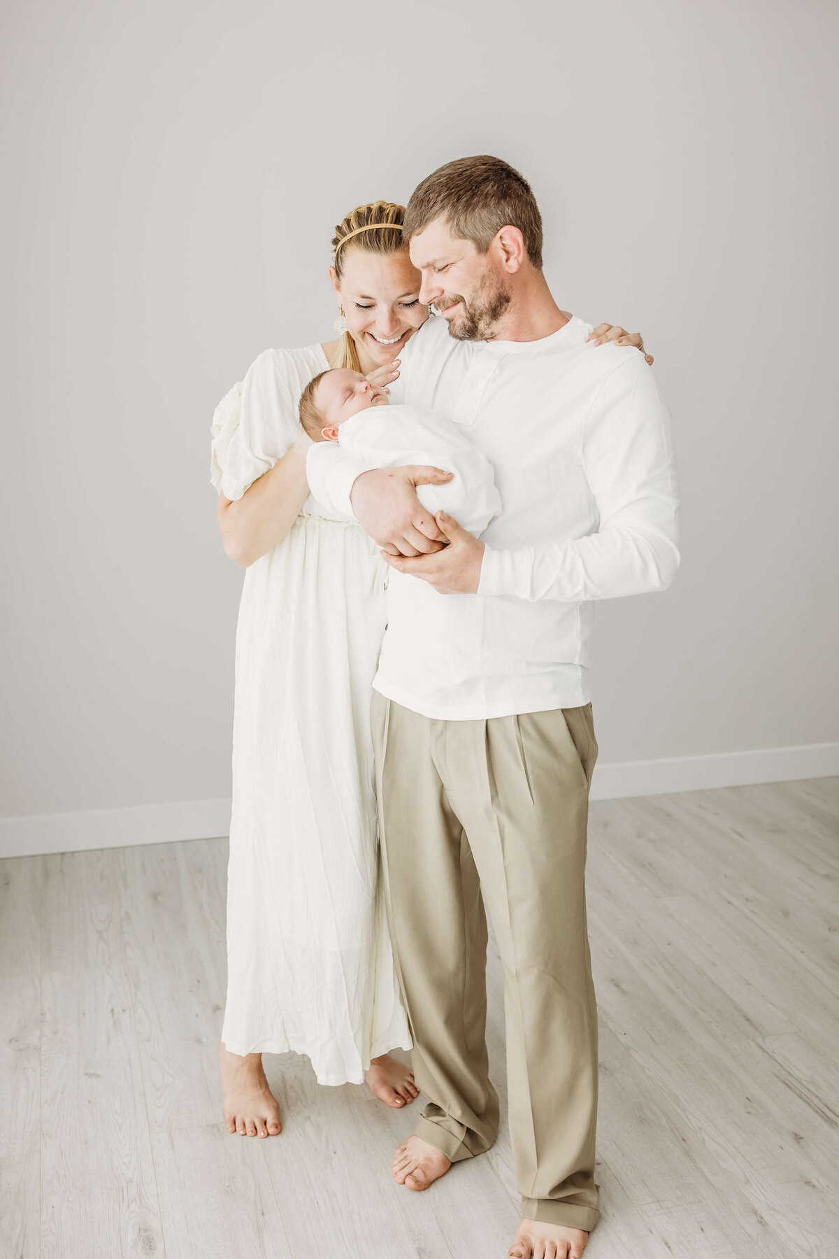 Happy couple in white and beige holding newborn son near Eau Claire, WI