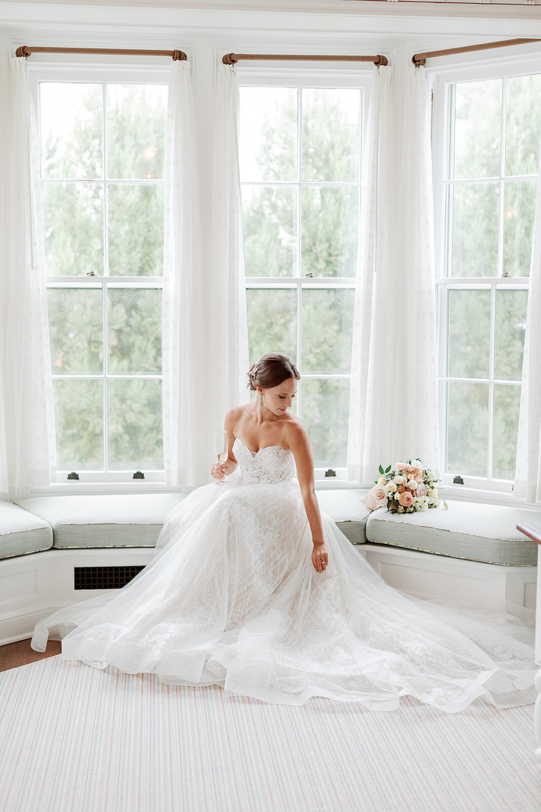 Bride in wedding gown relaxes in bay window