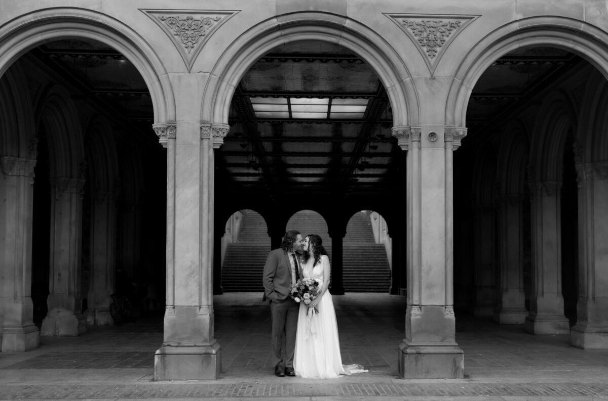The couple sharing a tender moment beneath Central Park’s beautiful stone arches.