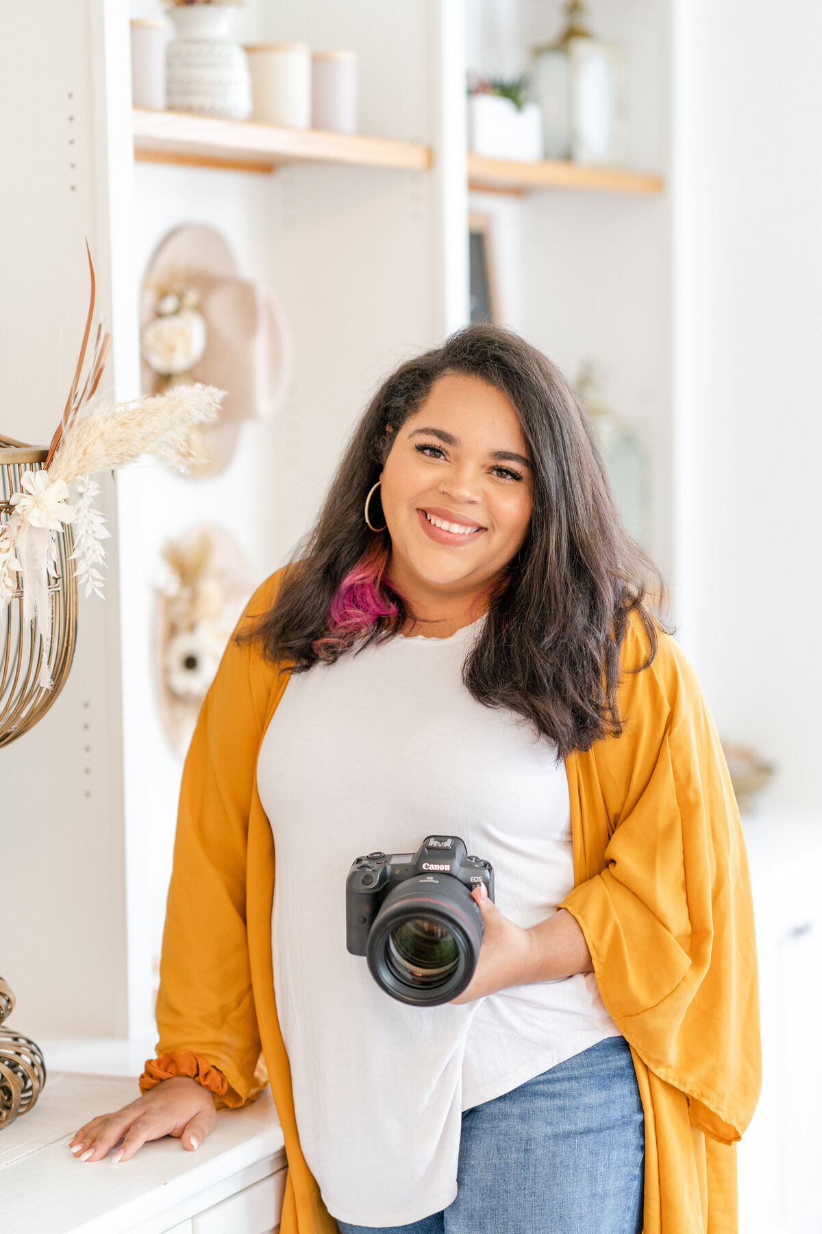 Woman standing holding camera and smiling  in an indoor decorated studio office in Houston