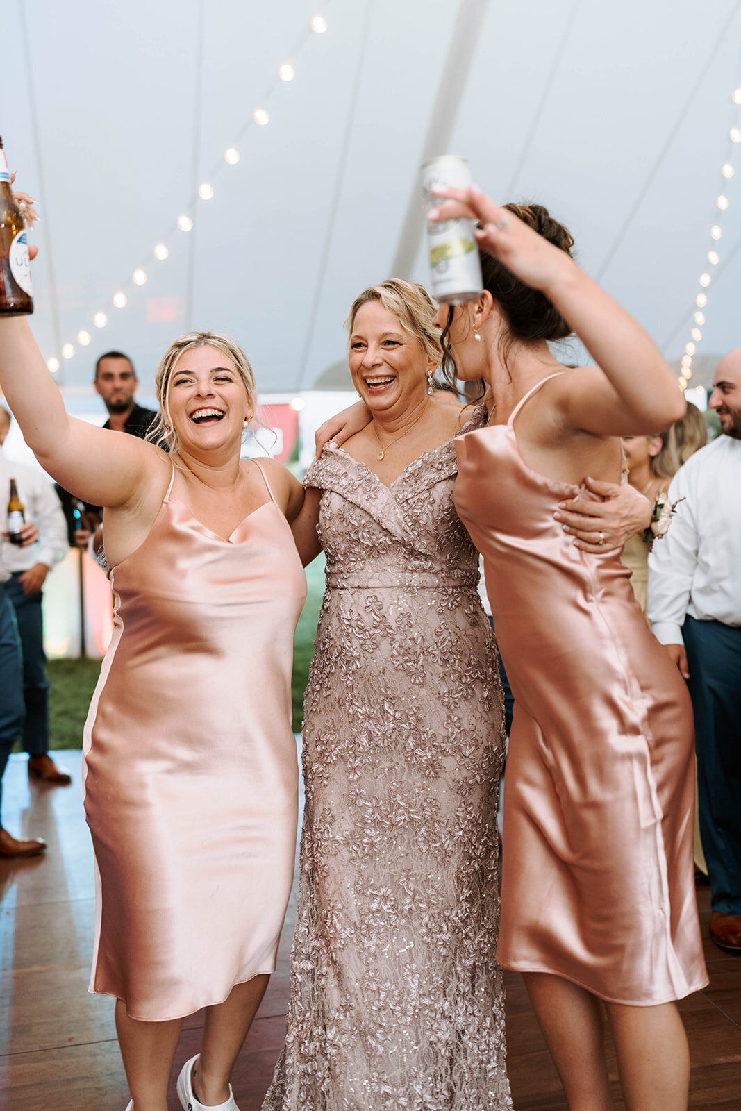 bridal party in blush dresses on dancefloor unders tented reception