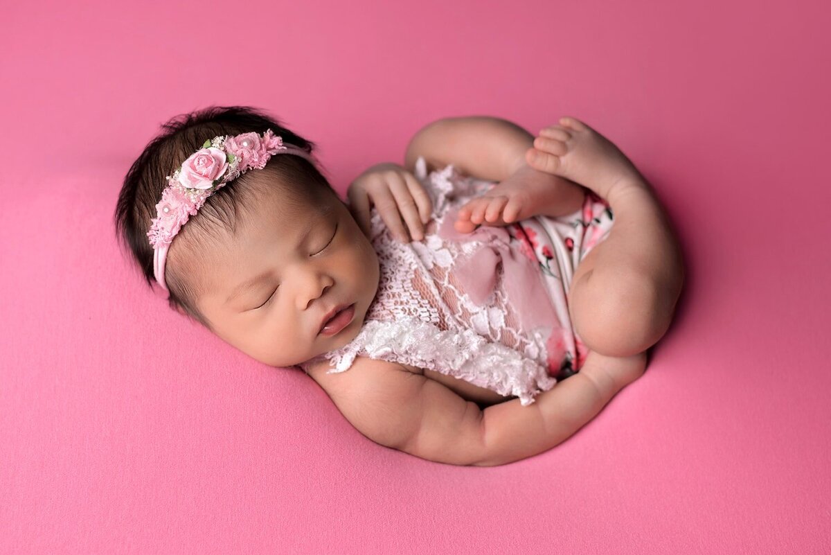 In-home newborn photo shoot of baby girl in pink flower romper