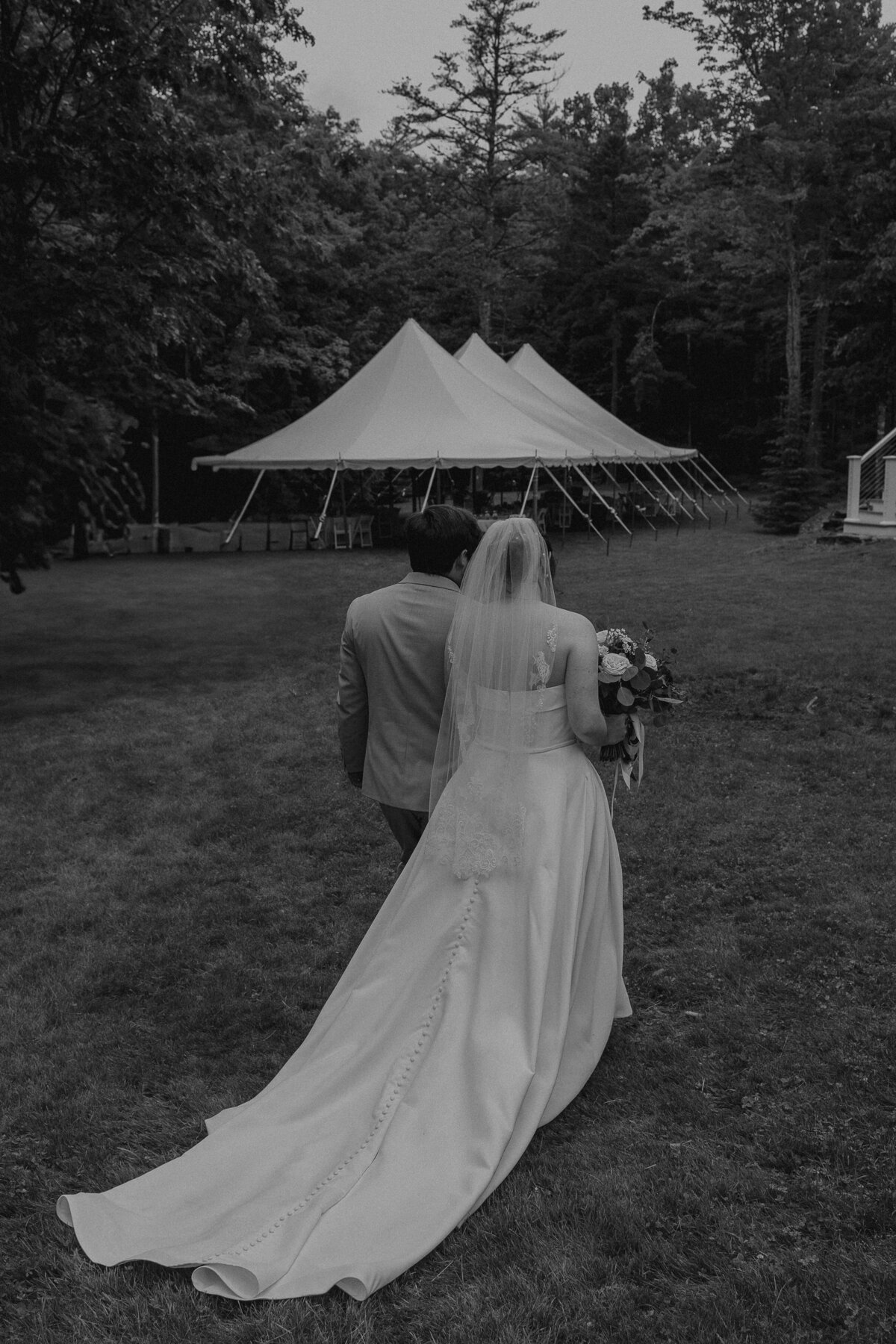 Balck and white photo of a couple walking away with their tent in the background