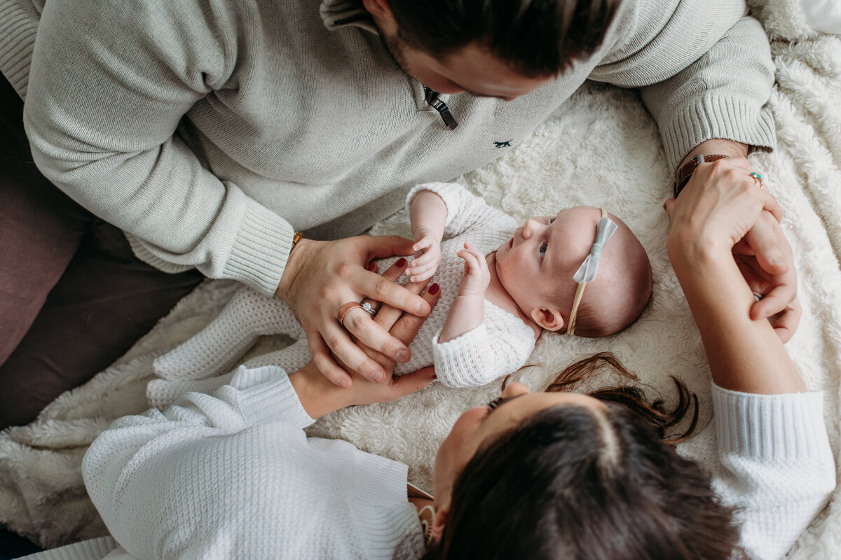 Family cuddles on the bed with their newborn baby and dog during a newborn photoshoot in Palatine, IL