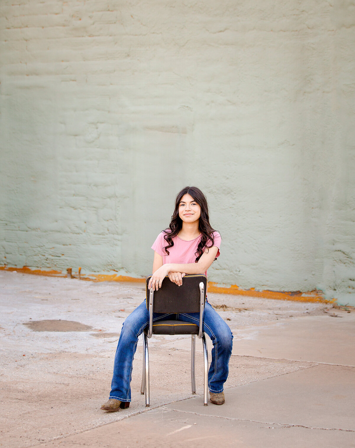 Senior girl sitting on chair against green wall in Plainview Tx