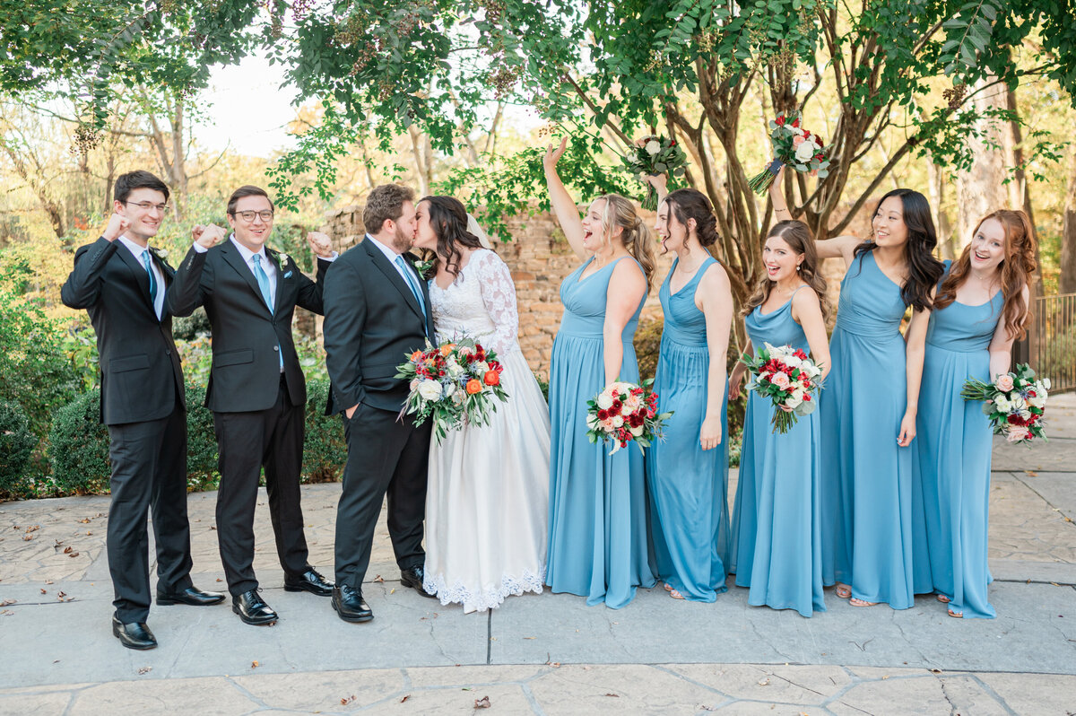 A newlywed couple with their wedding parties celebrating around them