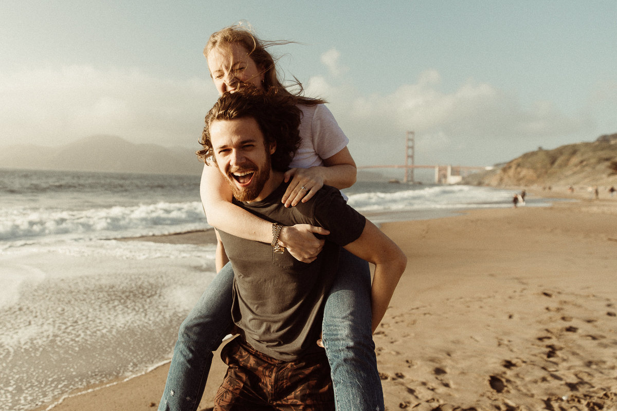 couple piggy back rides on the beach in San Francisco
