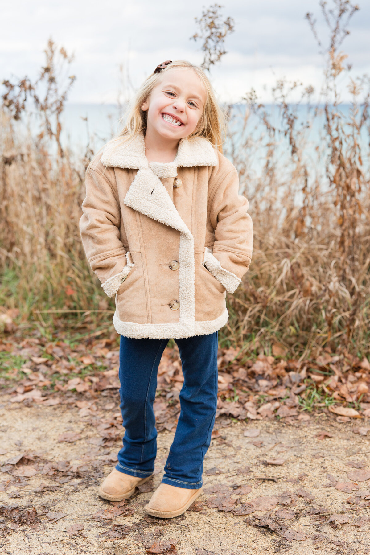 A little girl with her hands in her pockets and smiling