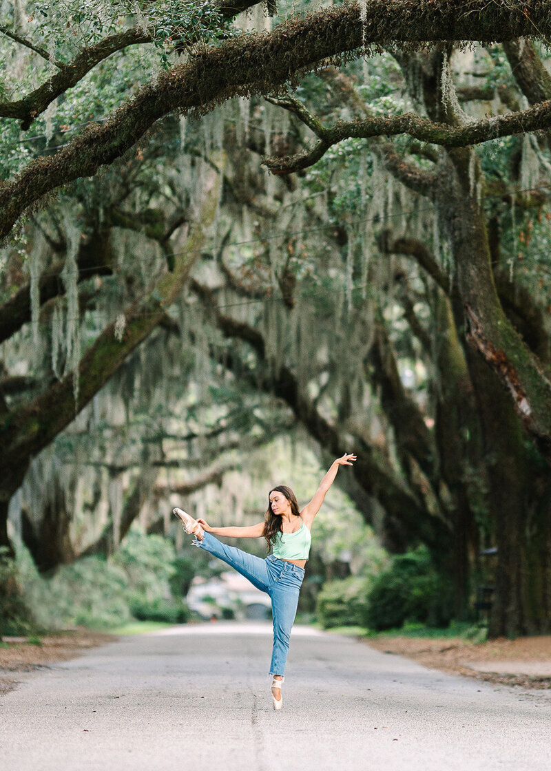 This senior photographer Charleston SC captured an incredible photo of a girl dancing under the mossy oak trees in Downtown Charleston