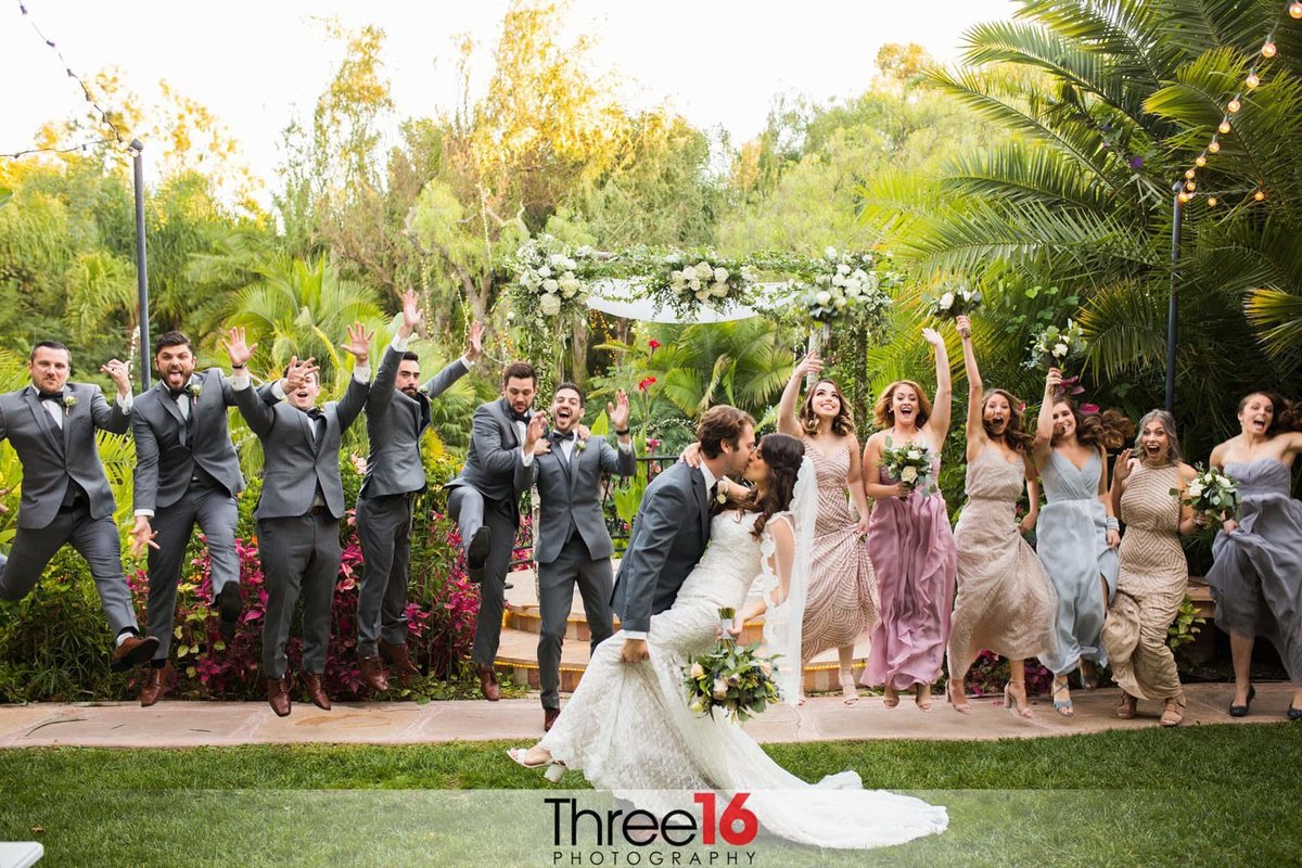Wedding Party jumps for joy as the new Bride and Groom share a kiss together