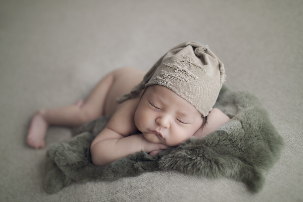 Baby boy in green sleeps for baby pictures in Colorado portrait studio