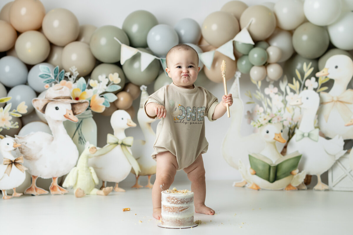 Baby girl with silly goose themed first birthday cake smash in Canton GA photography studio