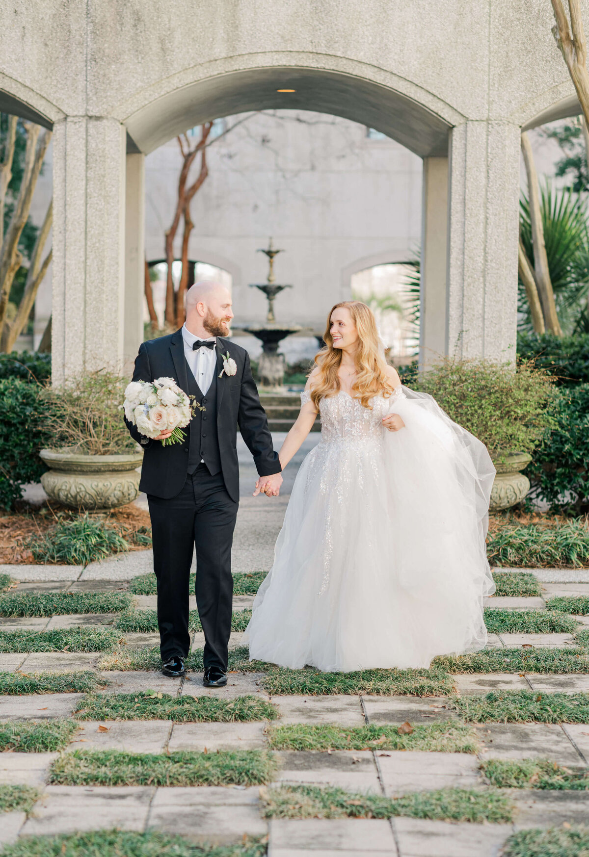Bride and groom walking towards camera in a garden courtyard