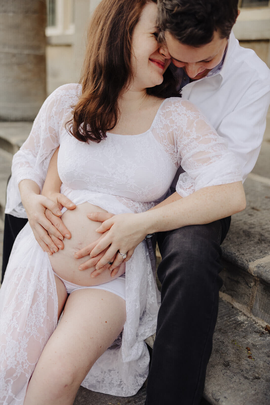Couple sitting on steps outside historical building at Finger Lakes maternity session, NY