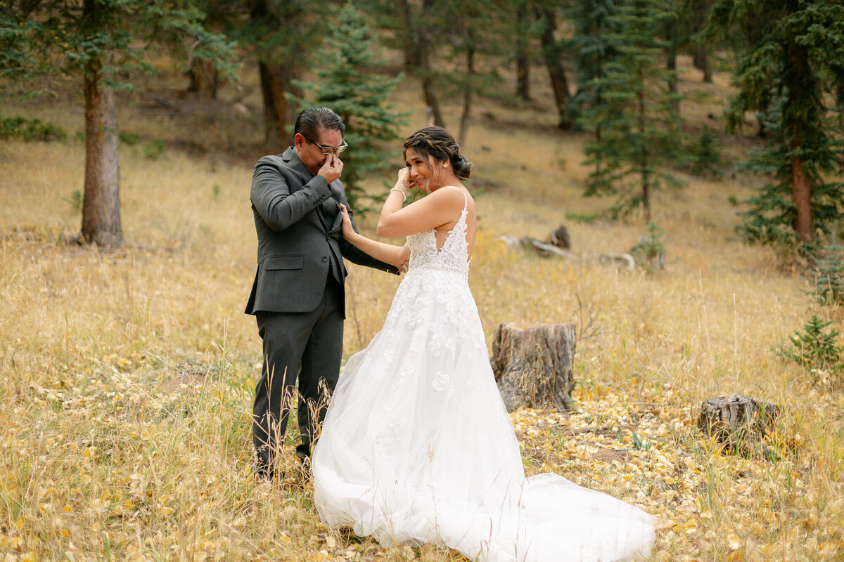 A bride wipes her tears away after her first look with her dad.