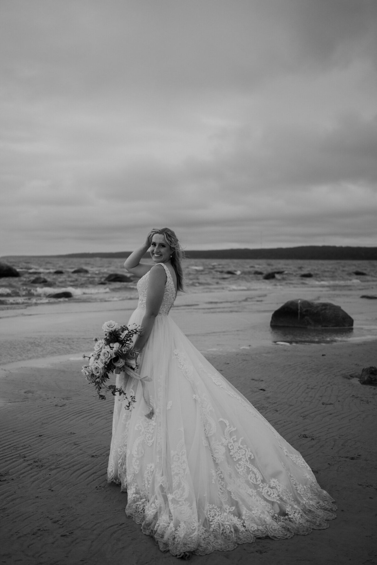 black and white image bride standing on beach