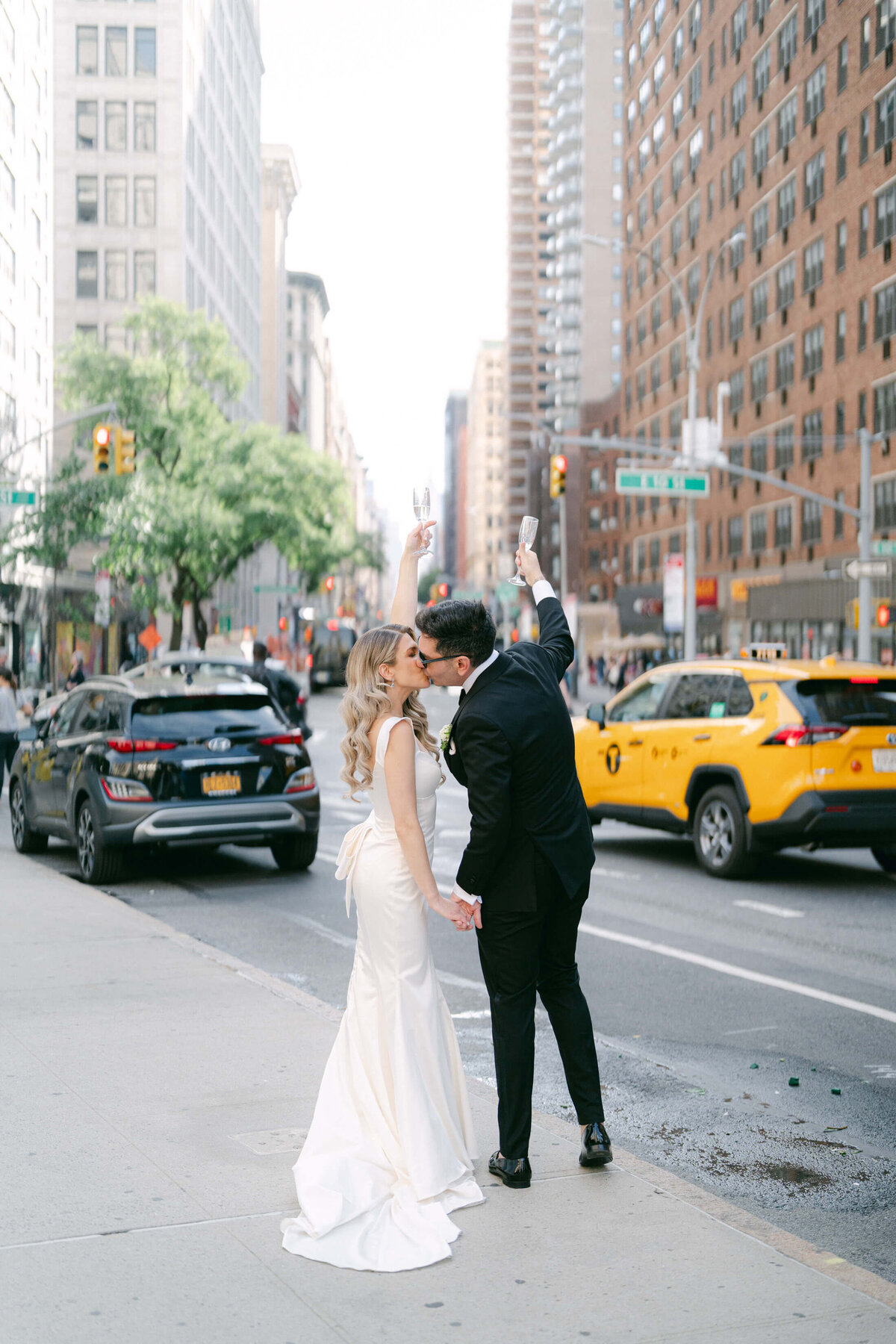 Bride and groom post-wedding ceremony on the streets of NYC toasting