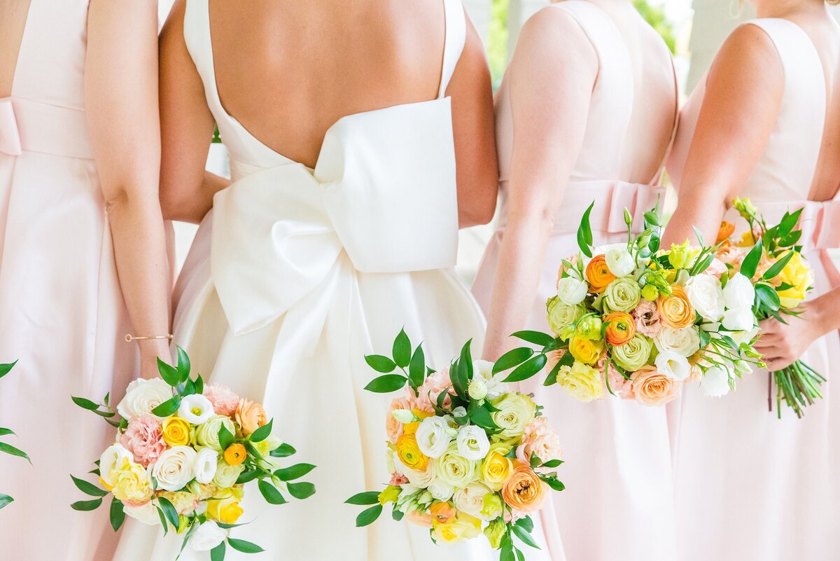 bride + bridesmaids holding their bouquets behind their backs