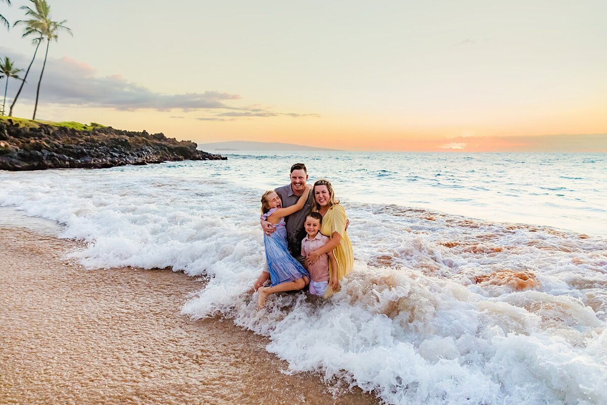 Family laughs and smiles at the camera while being photographed at Ulua Beach on the island of Maui by Love + Water