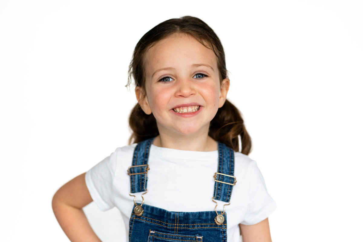 Girl in white shirt and overalls for preschool photo