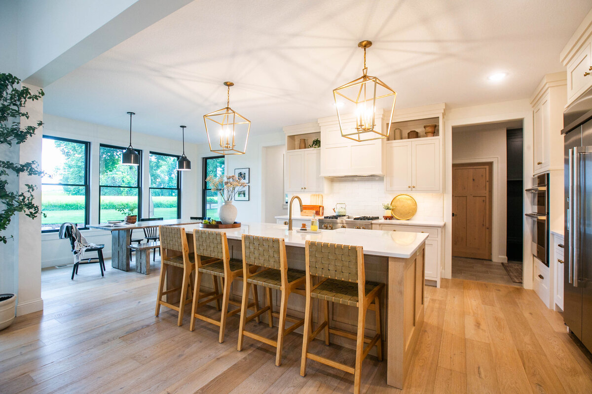 Open kitchen with white cabinets, large island, and quartz countertops in an Otsego custom home