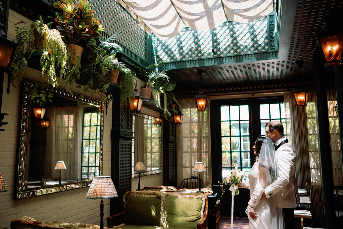 Bride and groom embracing inside Hotel Chelsea’s elegant interior in New York City, surrounded by vintage decor and greenery, captured during Japna and Chris’s intimate elopement by NYC wedding photographer Perry Hancock.