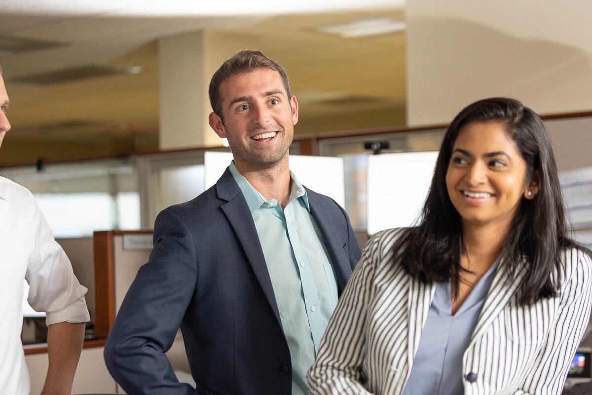 Two business people, a man and a woman, standing amidst cubicles