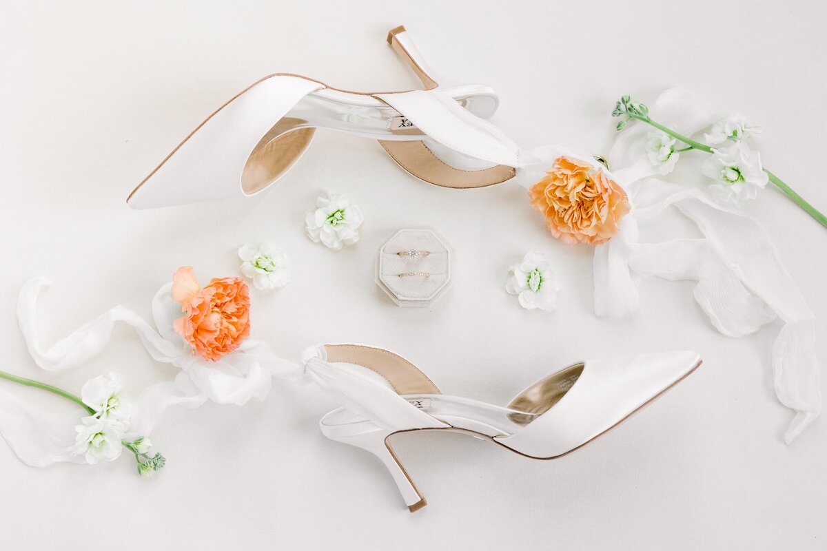 Flatlay of bridal shoes with rings and flowers