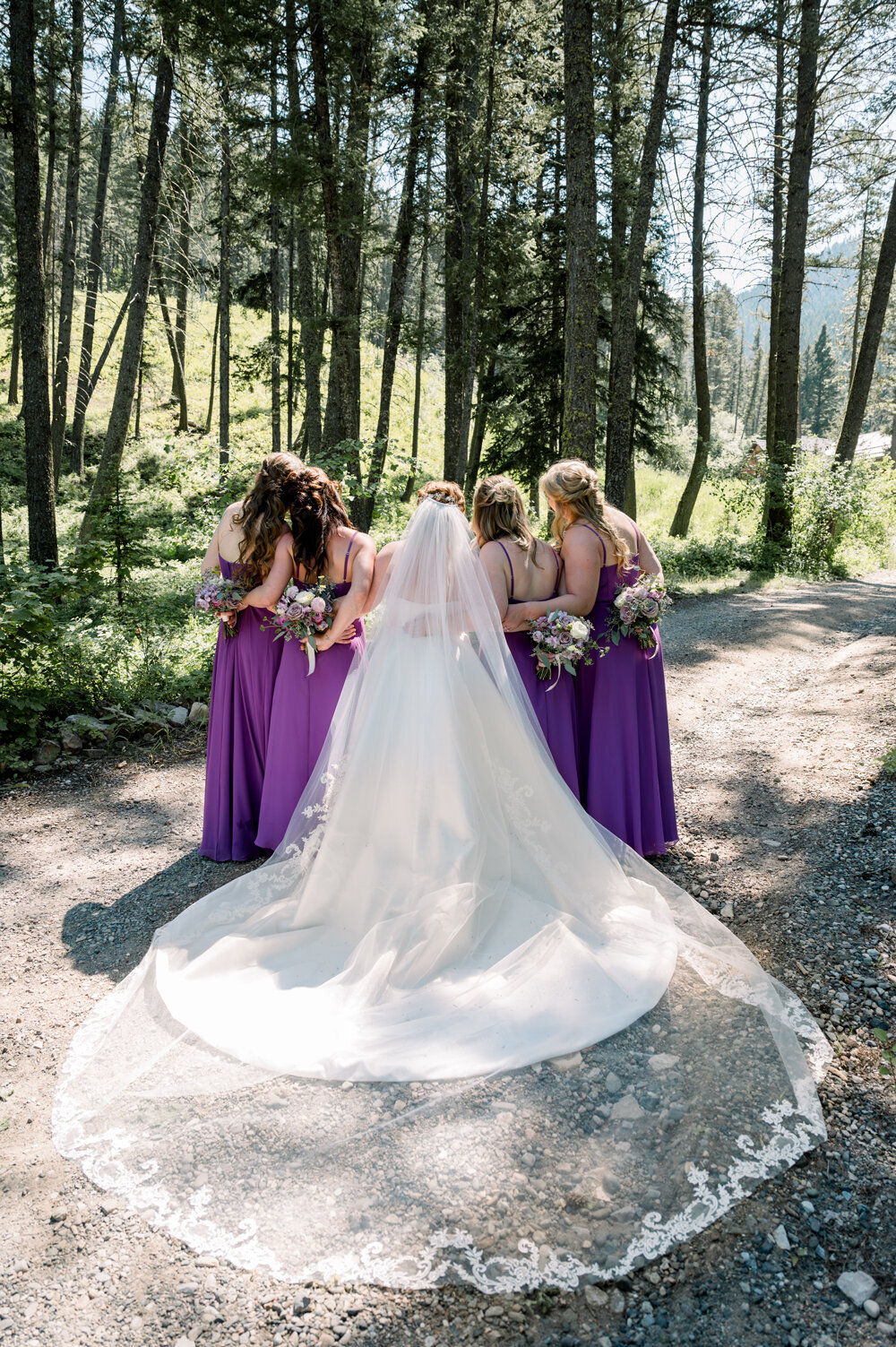 Bride and bridesmaids with  bouquets in shades of purple and blush, for a Montana summer wedding. 