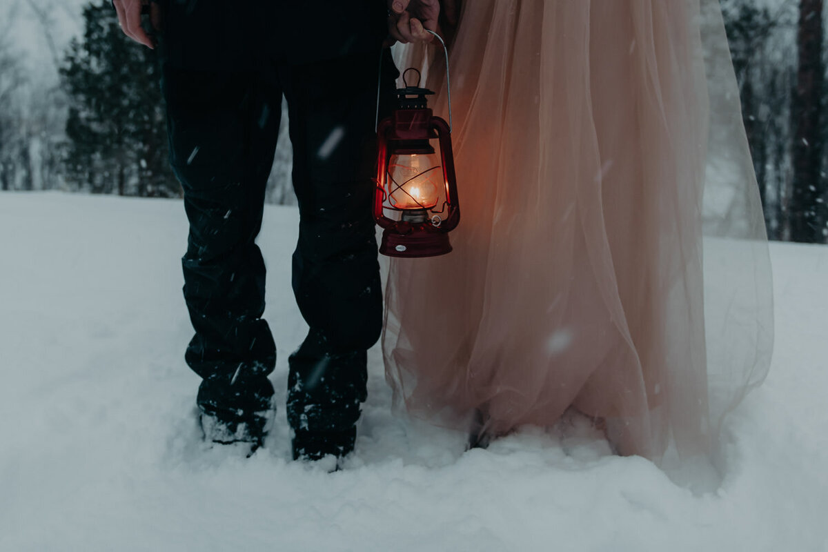 couple holding a lantern during their winter elopement  in norway