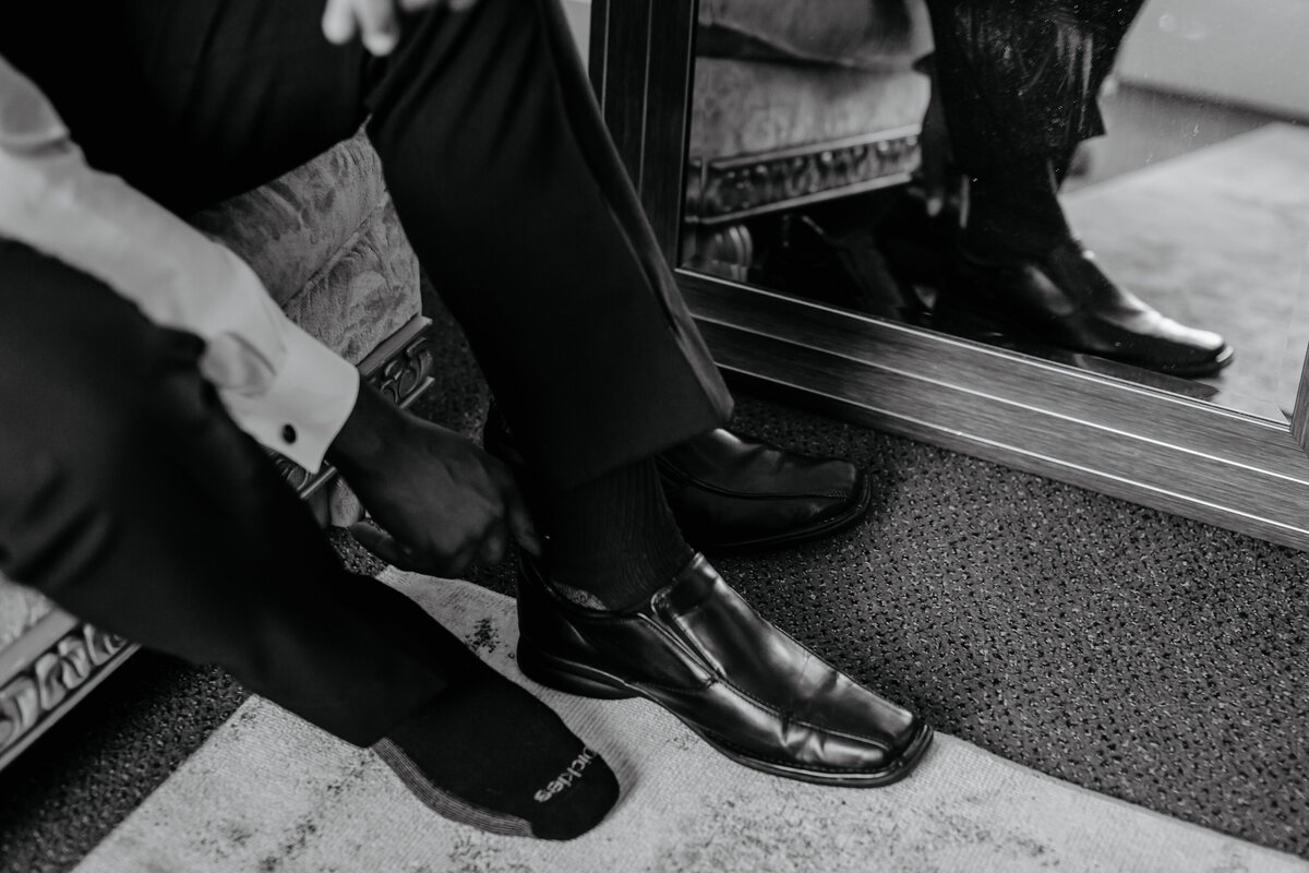 alt="groom putting on shoes for wedding day"