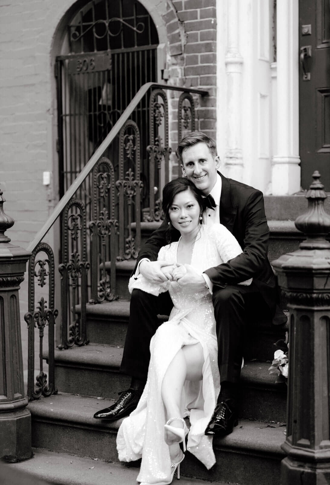The bride and the groom are sitting on a staircase along the streets of West Village, NYC. Image by Jenny Fu Studio