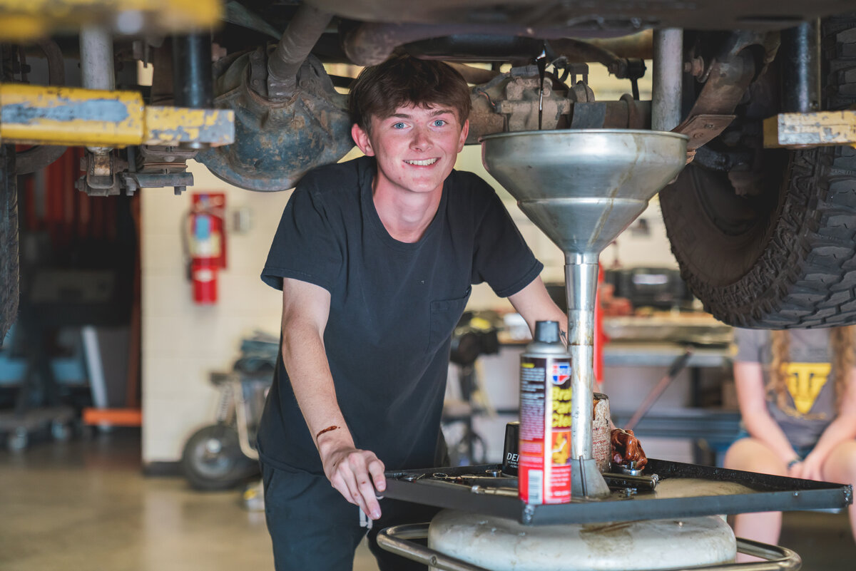 Male student getting ready to change the oil in his school's auto shop