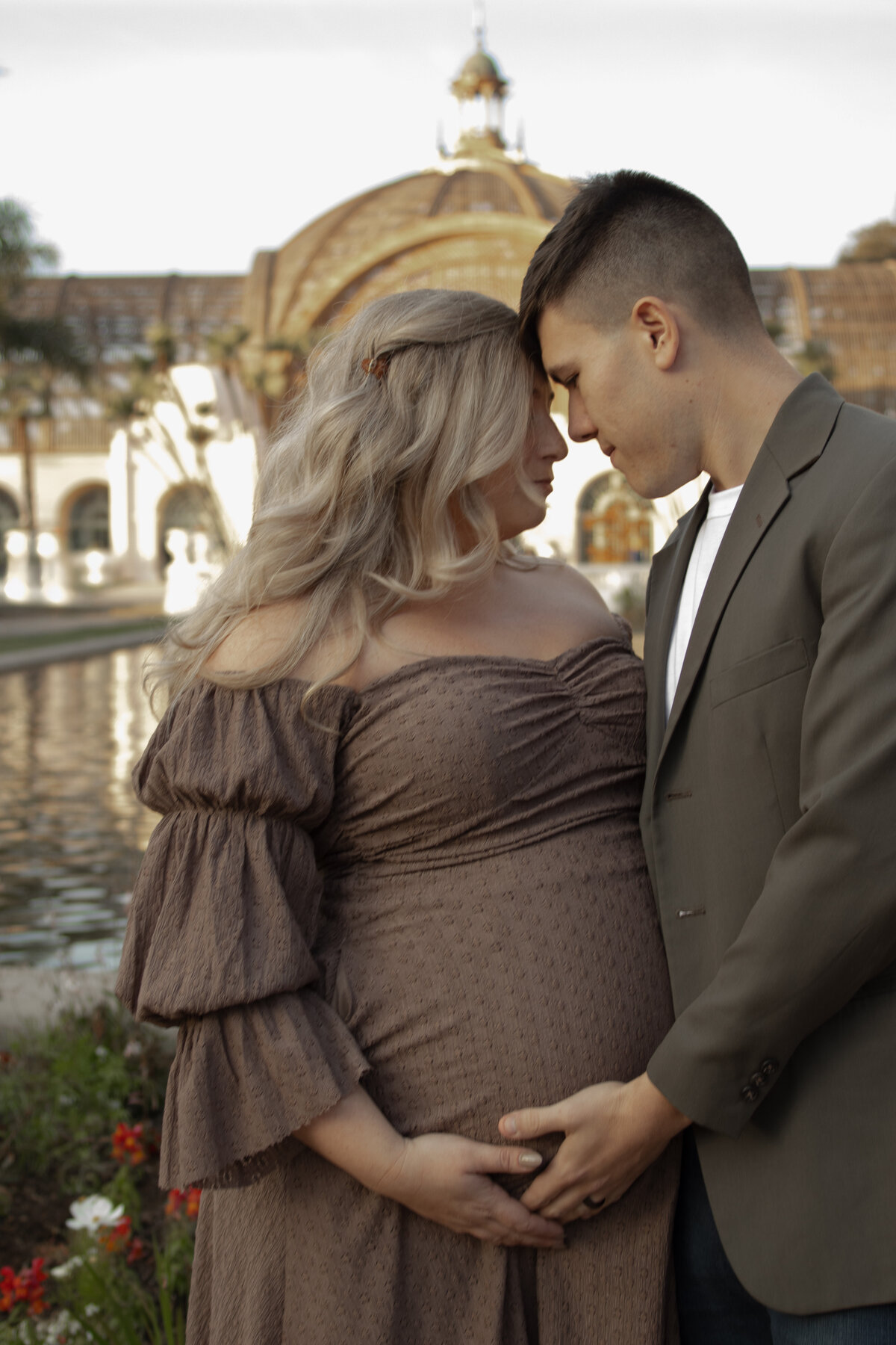 expecting mom and dad having an intimate moment in front of the botanical building in balboa park