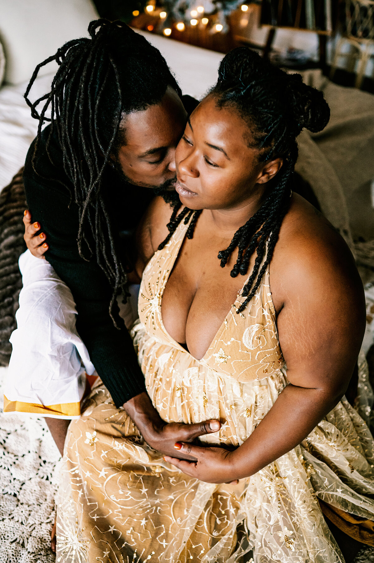 pregnant mother leaning into father as he holds her belly and kisses her head