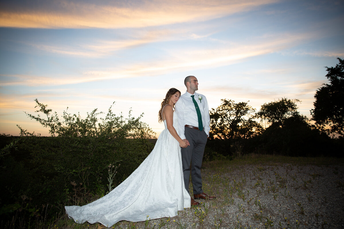 Austin wedding photographer captures a beautiful bride and groom standing in a field at sunset.
